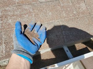 A contractor performing a roof inspection on a house, identifying issues that may need roof repair during the summer season.